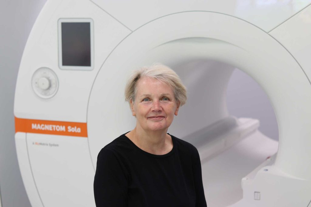 patient smiling in front of MRI scanner